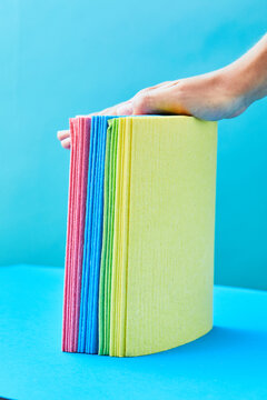 Hand of crop housewife with pile of colorful rags on two colored background in studio showing concept f household chores