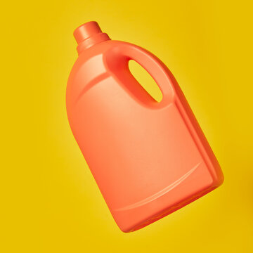 Bright plastic container from liquid detergent placed on vivid yellow background in studio