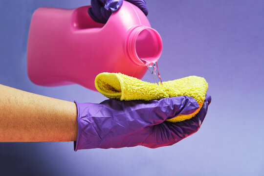 Crop anonymous person with plastic bottle pouring liquid detergent in a rag in studio