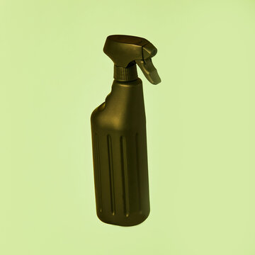 Black spray plastic container from liquid detergent placed on vivid pastel green background in studio