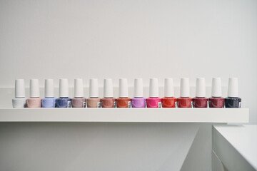 Set of colorful nail lacquers placed in row on shelf in modern beauty studio