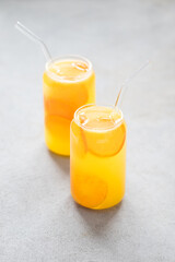 Fruit drink refreshing mandarin in a glass jar with a straw on a light background