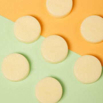 From above of natural round shaped soap arranged on two colored background in studio