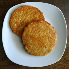 Potato pancakes on a white plate, fatty and unhealthy food, high-calorie and delicious dish.