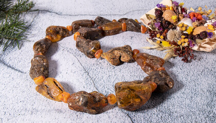 Unique big  natural yellow-green  necklace made of rare amber stone with plant and flower inclusions  beautifully laid out on a gray surface. 