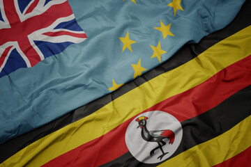 waving colorful flag of uganda and national flag of Tuvalu .