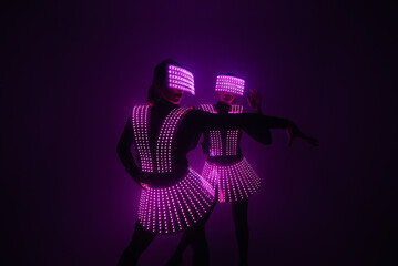 Two sexy disco dancers move in UV costumes. Parties and dances.