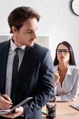 passionate secretary in eyeglasses seducing businessman on blurred foreground