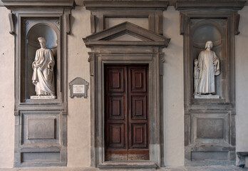 Fototapeta na wymiar Florence, Italy - 2020, January 18: Old wooden entry door to the Uffizi Gallery Museum. Cosimo and Lorenzo Medici marble statues on either side..