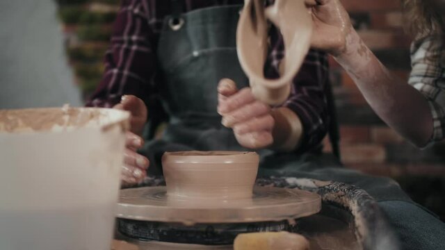 Potter masterclass, Man and woman are working with pottery wheel making pots during master class for adults, creative craftsman hobby. DIY Leisure activities and craftsmanship concept.