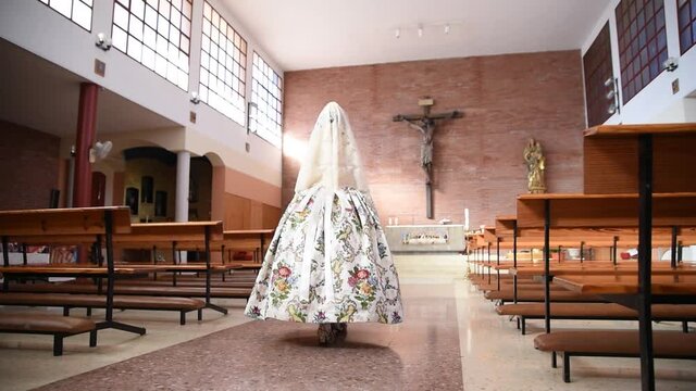 Fallera mayor of Valencia walking towards the altar of the cathedral. Woman walking towards church altar