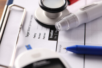 Lancet and blood glucose meter lying on clipboard with medical documents closeup