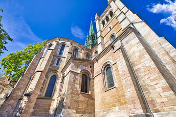 Bottom view of romanesque lateral facade, bell tower and gothic spire of Saint-Pierre Cathedral in a sunny day. Church in old historic town of Geneva in summer season, French-Swiss in Switzerland.