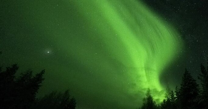 Green lights of the Northern Lights. Timelapse of the night sky with the Northern Lights. Film grain, lens flare.