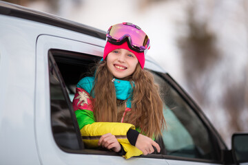 Happy girl enjoying winter sports, cheerful portrait of a girl in the car and in a ski mask, arrived at the ski resort, tourist travel for christmas holidays