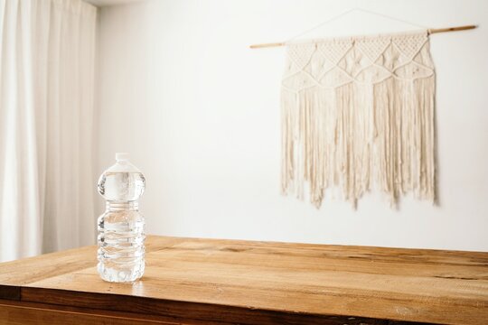 Full bottle of water placed on wooden table in light room with minimalist boho decor