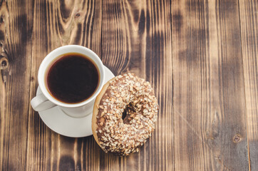 White cup of black coffee and donut with nuts.