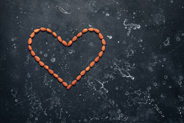 Heart shaped almonds on black stone grunge background. Valentine's Day. Top view.