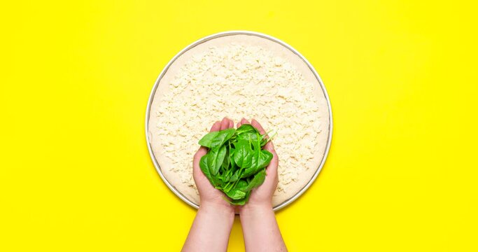 Cooking vegetarian pizza with spinach and feta, stop motion animation, flat lay. Preparing vegetarian pizza with spinach and feta, on yellow background, stop motion. Step by step pizza recipe .