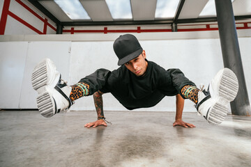 Full body of energetic young man doing acrobatic seated while performing break dance
