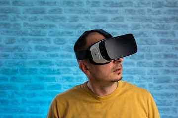 Portrait of happy man wearing vr goggles, experiencing virtual reality using 3d headset. man using virtual reality headset, VR, future, gadgets, technology concept. Blue neon background.