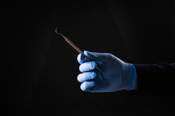 Detail of hand holding dental tool in dental clinic. Dental clinic.