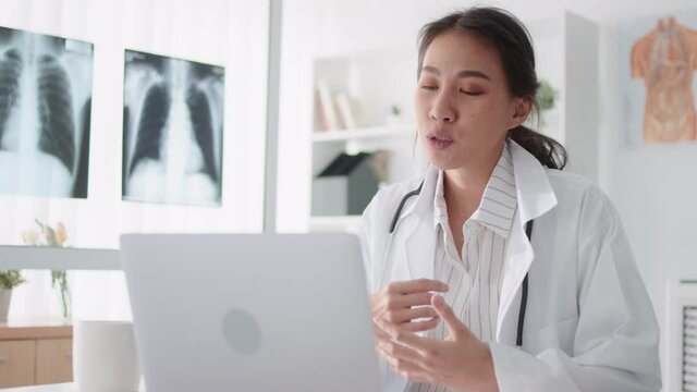 Asian female doctor using laptop computer online video call remote talking to patient, prescribe medicine. Tele medical, telehealth, hospital clinic health care service, or internet technology concept