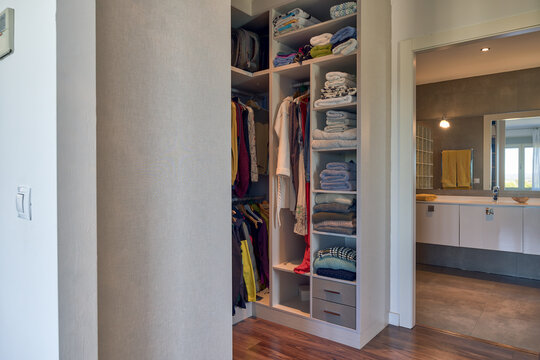 Comfortable closet with wooden shelves filled with various colorful clothes in contemporary apartment