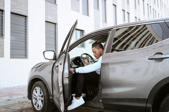 Side view of African American male sitting in expensive car looking down