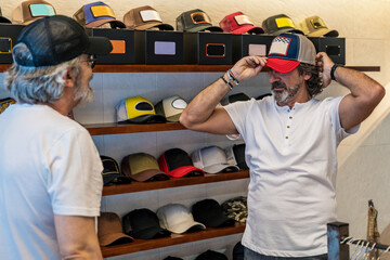 Side view of customer trying on cap in clothing store
