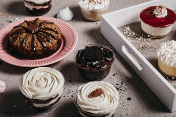 From above of chocolate cake and meringue cookies placed on table with desserts with whipped cream