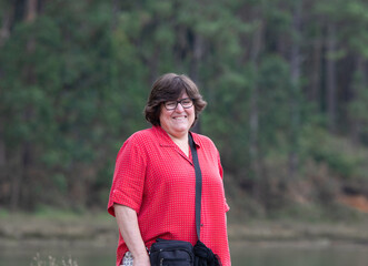 Fototapeta premium portrait of a pretty smiling middle aged woman on a wild beach surrounded by trees 