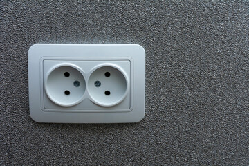 An electrical outlet on a gray, textured wall. Image for project and design. The concept of electrification, repair of electrical equipment.