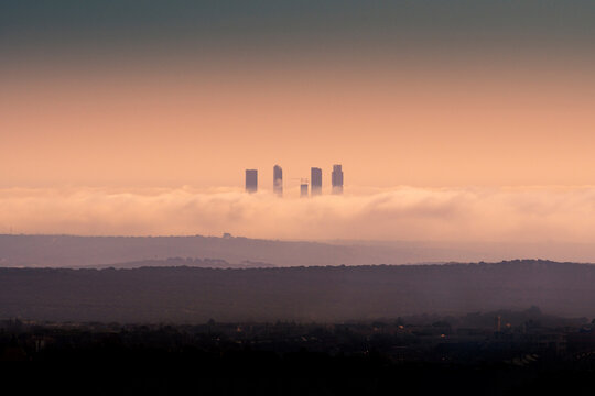 Amazing view of skylines of Cuatro Torres Business Area surrounded by thick clouds at sunset in Madrid