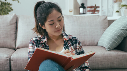 closeup asian woman with attentive look is keeping diary and touching chin with pencil while...