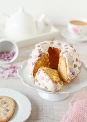 Homemade rustic bundt orange cake covered with white chocolate and heart shape candy sprinkles