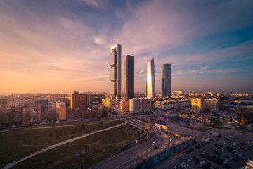 Cuatro Torres Business Area with skyscrapers reflecting bright sundown light in evening in Madrid