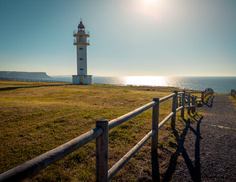 Road towards lighthouse located in front of sea in Cabo de Ajo against cloudless sunset sky