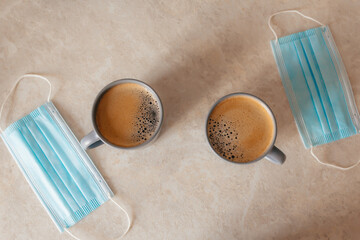 a couple of cups of coffee on the table, next to the medical masks. The concept of lifestyle, a new life in the pandemic. Valentine's Day during the coronovirus