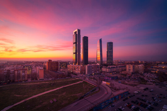Cuatro Torres Business Area with skyscrapers reflecting bright sundown light in evening in Madrid