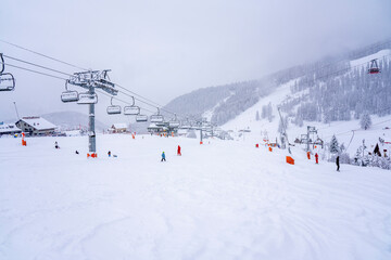 Fototapeta na wymiar Auron, France - 01.01.2021: Downhill skiing during a heavy snowfall. Professional ski instructors and children on a resort slope in mountains. Blurred focus background. High quality photo