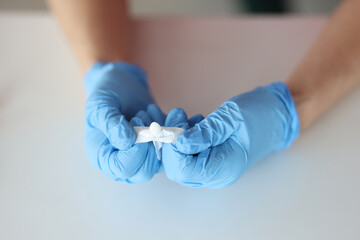 Doctors hands in rubber gloves opening rectal suppository closeup