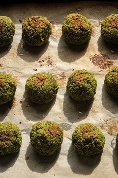 Top view of crispy baked green edamame falafel balls arranged in rows on baking paper during food preparation
