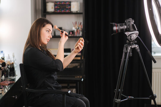 Young beautiful woman and professional beauty make up artist blogger recording makeup tutorial in beuty studio to share on website or social media. Woman use ring lamp and digital camera