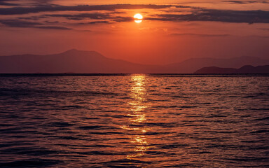 orange fiery sundown sky with some clouds over calm sea, nature background.
