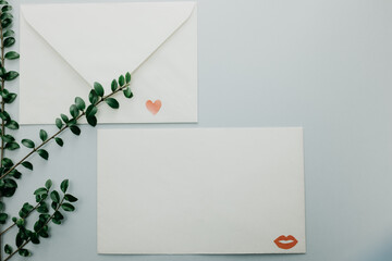 Minimal composition with a white envelope, heart and green leaves