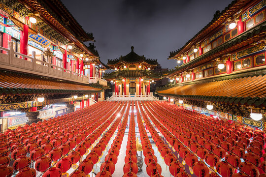 Majestic view of illuminated Sanfeng Temple built in traditional oriental style with red and golden colors in night time in Kaohsiung city in Taiwan
