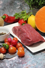a piece of beef on a plate, colorful vegetables, tomatoes, peppers and large orange pumpkins cut in half