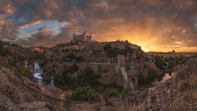 Aerial view of aged town with medieval houses located on shore of river against cloudy sky at sunset