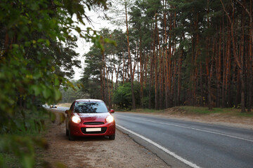 Fototapeta na wymiar Red car parked near forest. Road trip